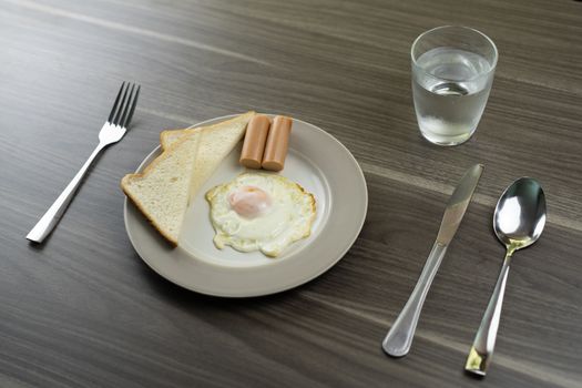 Breakfast on a white plate on the wooden floor.
