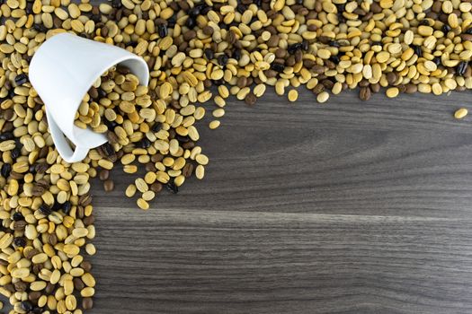 White coffee cup and raw coffee beans in the upper right corner, wooden floor