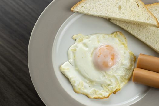 Close-up of breakfast on a white plate in the bottom right corner of the wooden floor