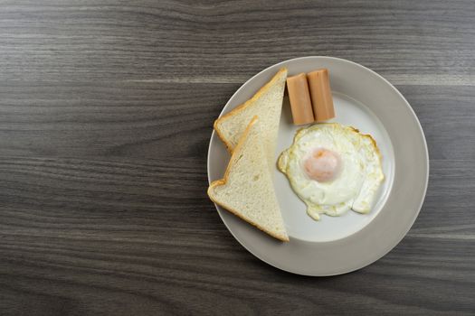 Breakfast on a white plate on the right corner of the wooden floor