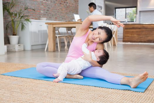 Happy mother and baby daughter exercising on mat at home