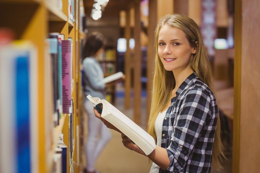 Serious students reading next to bookshelf in library