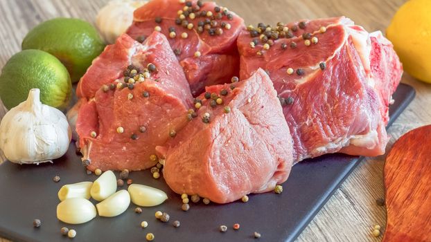 Cooking for lunch the fresh diet of red meat for gourmets. Red meat on a black Board sprinkled with pepper, garlic, anise and lime. Billets for barbecue,  steak or shish kebabs