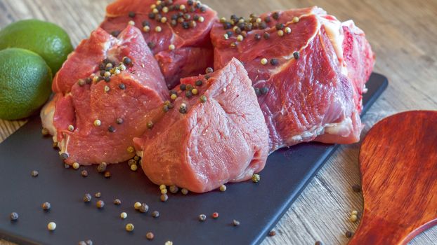 Red meat on a black Board sprinkled with pepper, garlic, anise and lime. Billets for barbecue,  steak or shish kebabs. Cooking for lunch the fresh diet of red meat for gourmets.