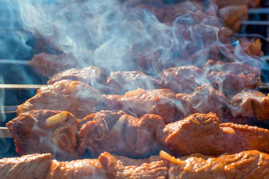 Meat on grill. Morning BBQ. Cooking barbecue on the grill with smoke. Cook fresh marinated meat with onions. Grill marinated barbecue is prepared on the grill on the coals.