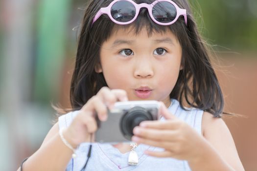  Cute little girl with compact digital camera is feeling amazing with her shot on travel in Thailand