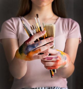 colored female artist hands holding paintbrushes