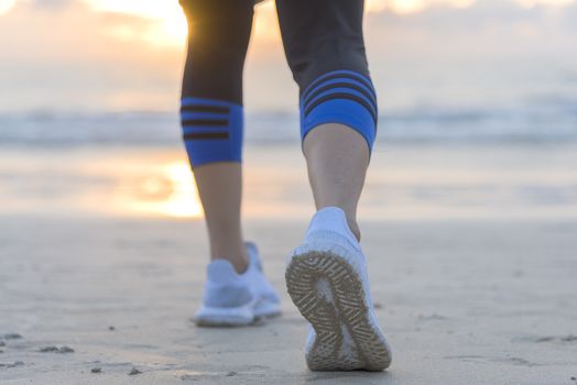 Woman running on the beach at sunrise closeup on shoe. Patong beach, Phuket, Thailand