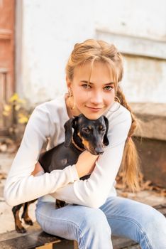 Pet care concept. Young woman hugging her dachshund dog outdoors. Focus on woman face