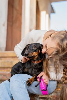 Pet care concept. Young woman hugging her dachshund dog outdoors