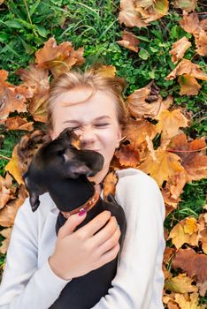 Pet care concept. Teenager girl playing with her dachshund dog on the grass