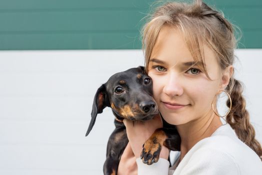 Pet care concept. Teenager girl hugging her dachshund dog