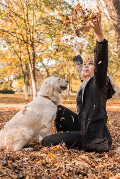 Pet care concept. Happy blond woman playing with her retriever dog in autumn park