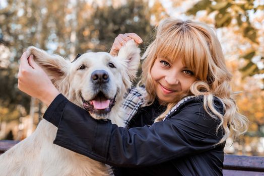 Pet care concept. Young smiling woman showing ears of her retriever dog in the park