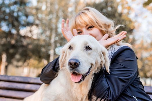 Pet care concept. Young smiling woman showing horns of her retriever dog in the park
