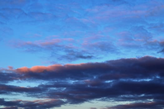 Beautiful panorama of orange and yellow clouds at sunrise and sunset in a blue sky