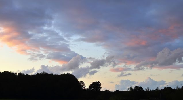 Beautiful panorama of orange and yellow clouds at sunrise and sunset in a blue sky