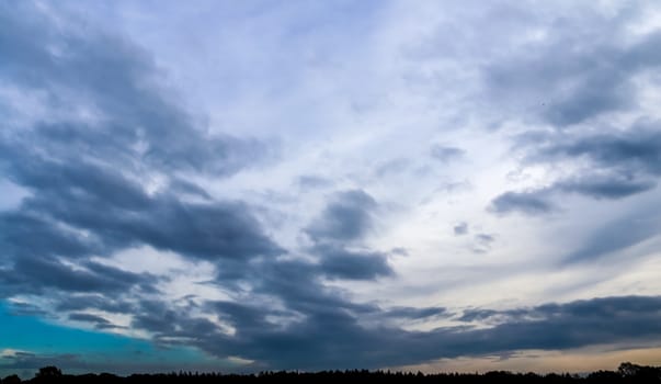 Beautiful panorama of orange and yellow clouds at sunrise and sunset in a blue sky