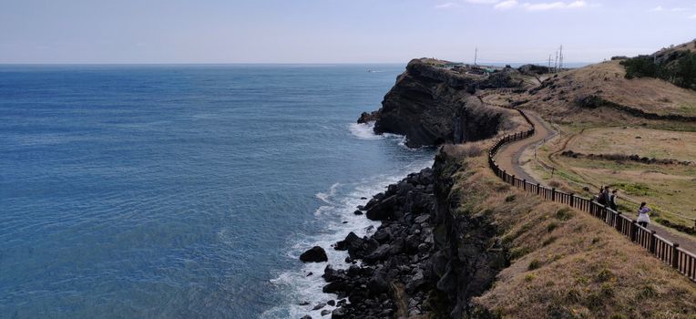 Songaksan wavy dirt path and rock beach overlooking blue ocean in Jeju Island, South Korea