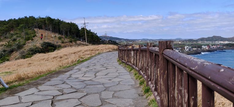 A paved path on the songaksan mountain with fence in Jeju Island, South Korea