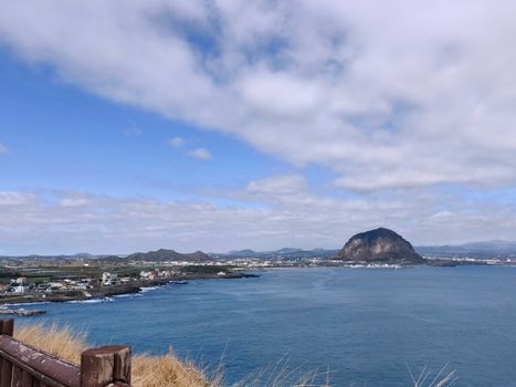 landscape view of Sanbang-san mountain seen from across the bright blue ocean in Jeju Island, South Korea
