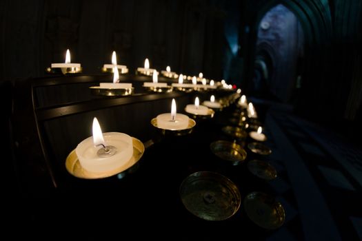 5 rows of prayer candles run from left to right in this wide angle photo from a cathedral