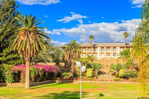 Park and garden with yellow palace building hidden behind tall palms, Windhoek, Namibia