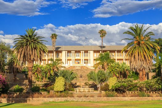 Park and garden with yellow palace building hidden behind tall palms, Windhoek, Namibia