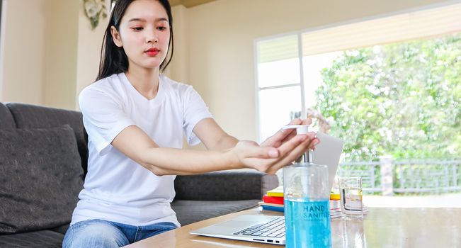 Asian Business woman working from home and she is Cleaning her hands with sanitizer gel for protective coronavirus .She is quarantined at home during the coronavirus epidemic.