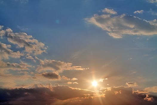 Beautiful view at bright sunbeams with some lens flares and clouds in a blue sky