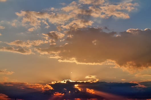 Beautiful view at bright sunbeams with some lens flares and clouds in a blue sky