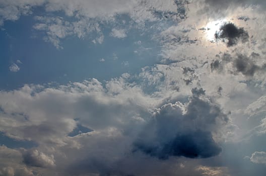 Beautiful view at bright sunbeams with some lens flares and clouds in a blue sky