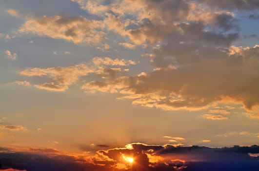 Beautiful view at bright sunbeams with some lens flares and clouds in a blue sky