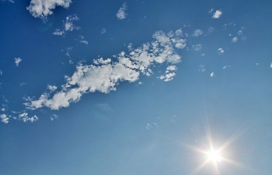 Beautiful view at bright sunbeams with some lens flares and clouds in a blue sky