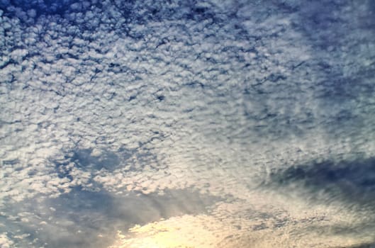 Beautiful view at bright sunbeams with some lens flares and clouds in a blue sky