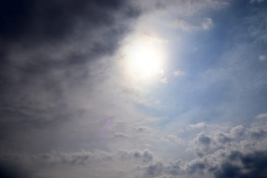 Beautiful view at bright sunbeams with some lens flares and clouds in a blue sky