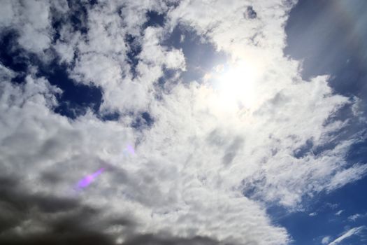 Beautiful view at bright sunbeams with some lens flares and clouds in a blue sky