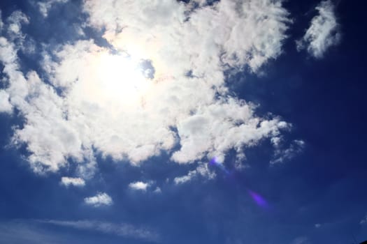 Beautiful view at bright sunbeams with some lens flares and clouds in a blue sky