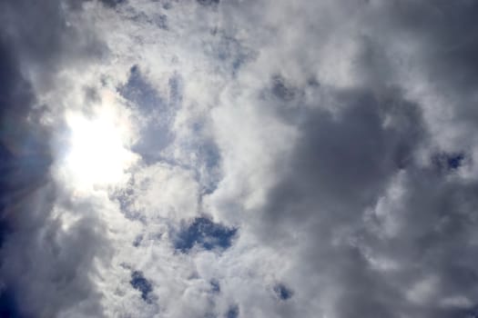 Beautiful view at bright sunbeams with some lens flares and clouds in a blue sky