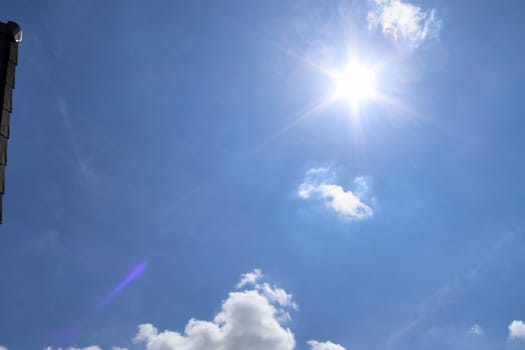 Beautiful view at bright sunbeams with some lens flares and clouds in a blue sky