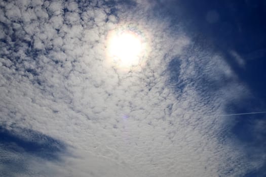 Beautiful view at bright sunbeams with some lens flares and clouds in a blue sky