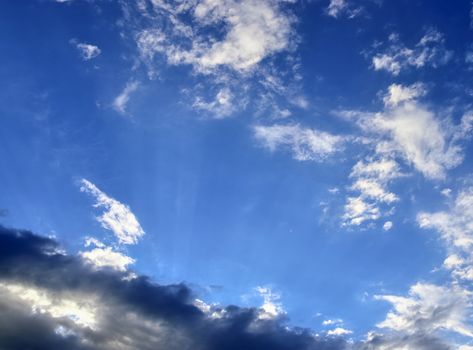 Beautiful view at bright sunbeams with some lens flares and clouds in a blue sky