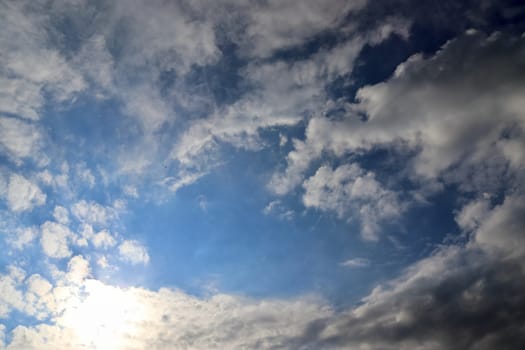 Beautiful view at bright sunbeams with some lens flares and clouds in a blue sky