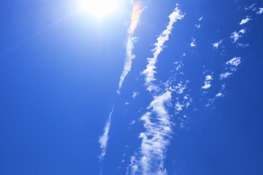 Beautiful view at bright sunbeams with some lens flares and clouds in a blue sky