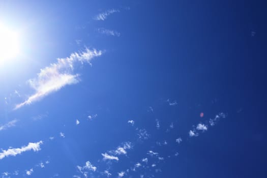 Beautiful view at bright sunbeams with some lens flares and clouds in a blue sky