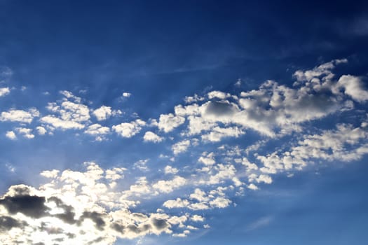 Beautiful view at bright sunbeams with some lens flares and clouds in a blue sky