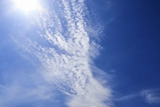 Beautiful view at bright sunbeams with some lens flares and clouds in a blue sky