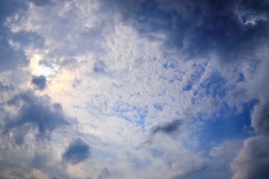 Beautiful view at bright sunbeams with some lens flares and clouds in a blue sky