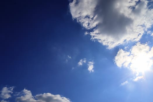 Beautiful view at bright sunbeams with some lens flares and clouds in a blue sky