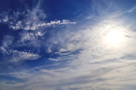 Beautiful view at bright sunbeams with some lens flares and clouds in a blue sky